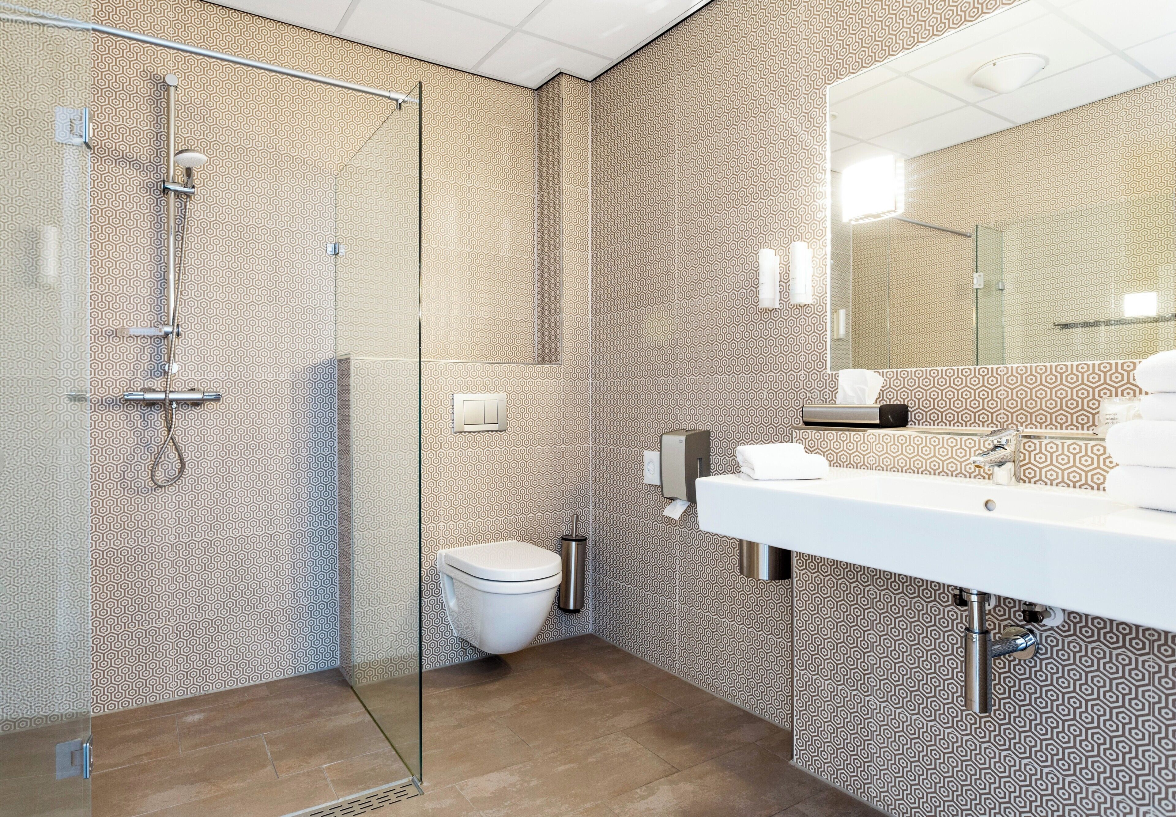 A modern bathroom with a glass shower enclosure, a white toilet, and a large mirror above a white sink.