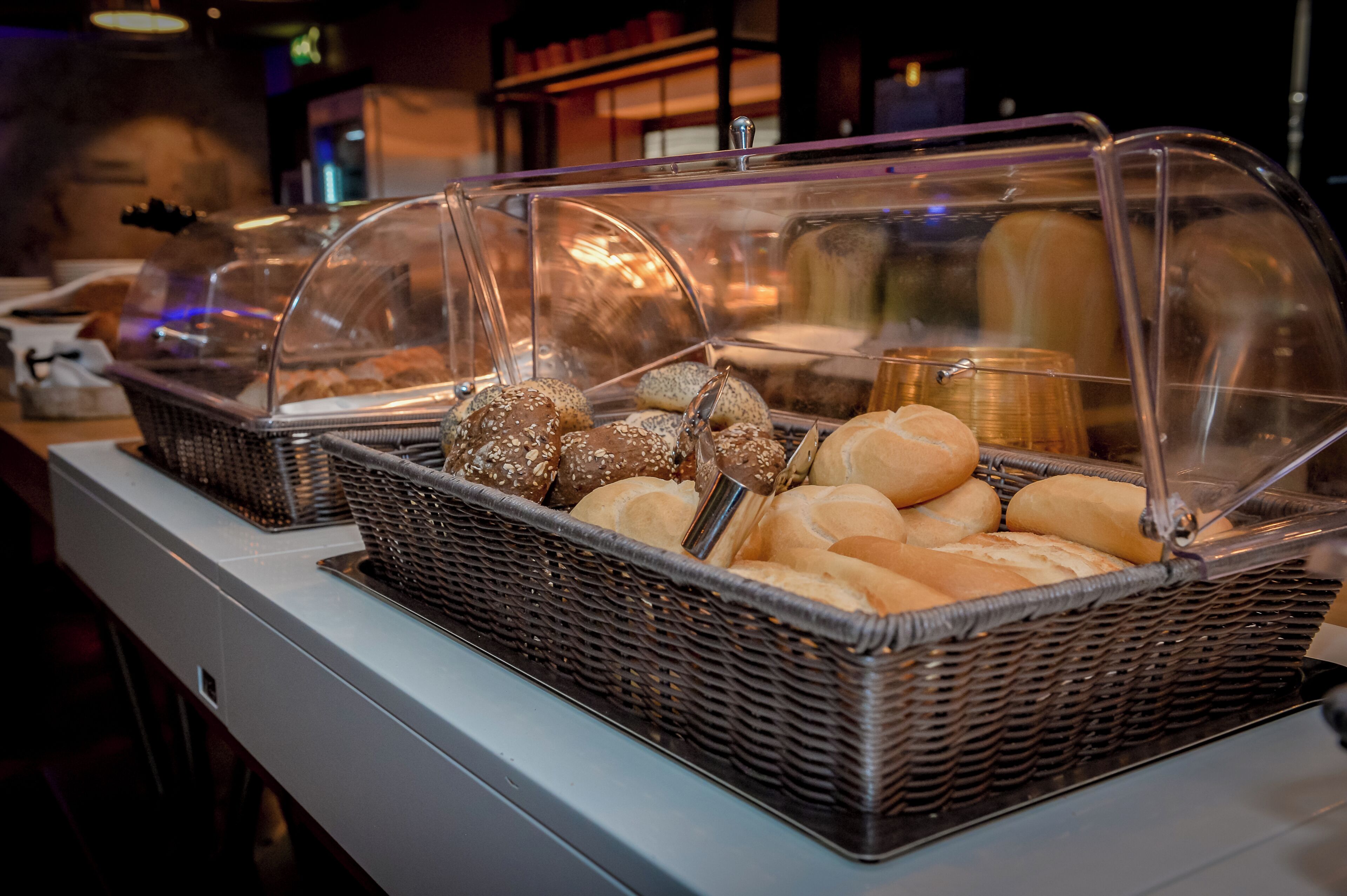 A buffet with various baked goods under glass covers.