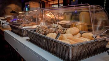 A buffet with various baked goods under glass covers.