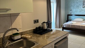 Een kleine hotelkamer met kitchenette, een bed en een badkamer.