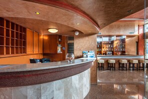 A modern bar area with a curved marble counter, wooden shelves, and a seating area with bar stools. - Comfort Hotel (Rhodes)