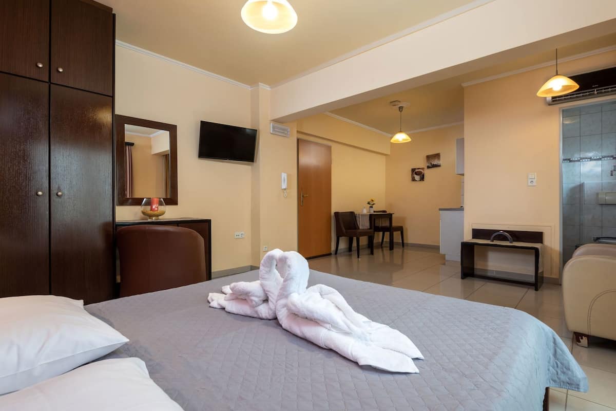Una habitación de hotel con cama, escritorio, silla, televisor y baño.