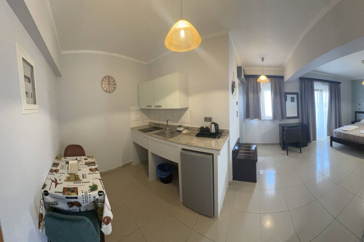 Habitación de hotel compacta con kitchenette, cama, escritorio y silla.