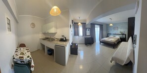 A compact hotel room with a kitchenette, a bed, a desk, and a chair. - Comfort Hotel (Rhodes)