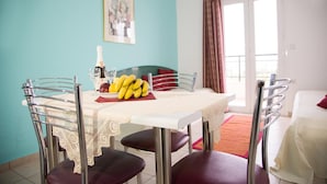 Een eetgedeelte met een tafel gedekt voor twee personen, een fles champagne en een schaal bananen.