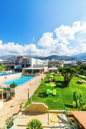 A resort with a swimming pool, green lawn, and lounge chairs. - Theoni Apartments (Hersonissos)