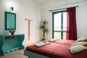 A bedroom with a bed, a desk, a potted plant, and a window with curtains.