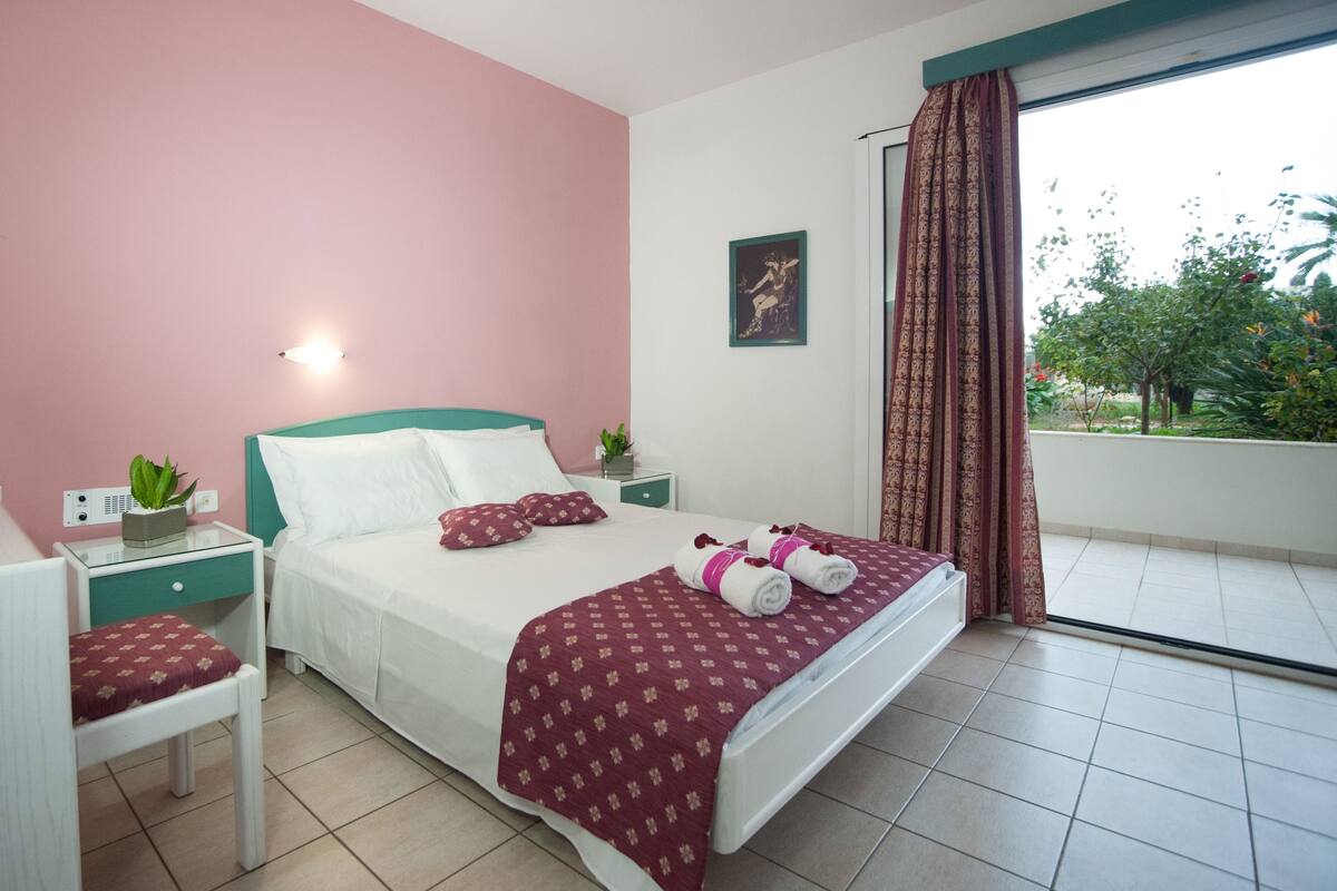 A bedroom with a bed, bedside tables, a desk, and a chair.