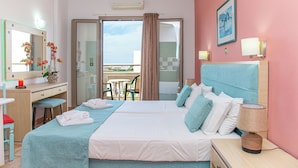Een hotelkamer met twee bedden, een bureau, een stoel, een balkon en uitzicht op de lucht.