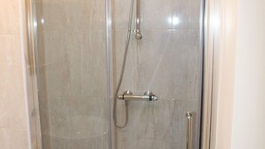 A glass-enclosed shower stall with a handheld showerhead and a handheld faucet. - Avenue Inn (London)