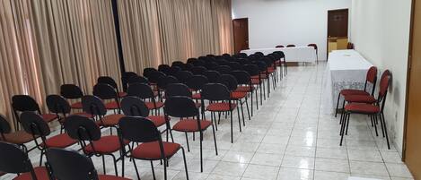 A conference room with rows of chairs, a white table, and an air conditioning unit.