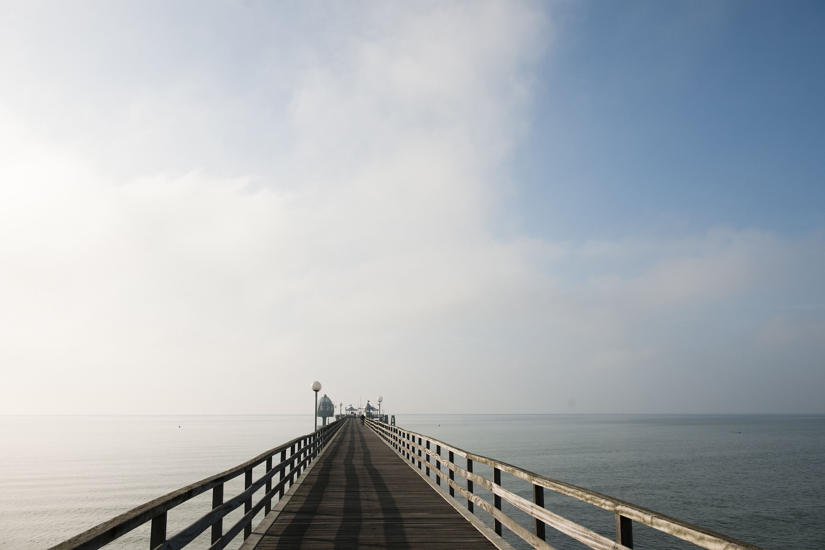 Une longue jetée s’étendant dans des eaux calmes, sous un ciel dégagé.