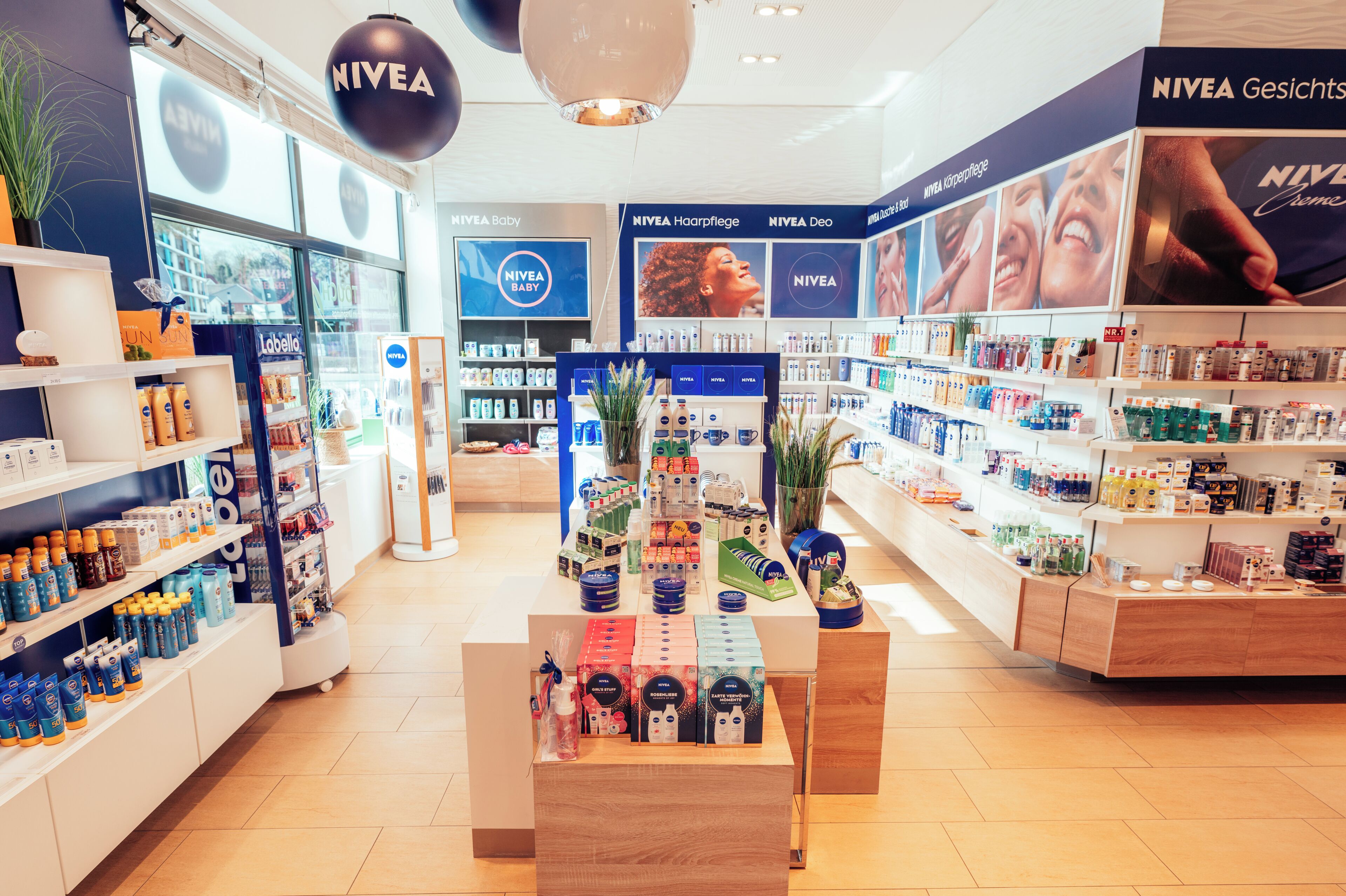 Una tienda Nivea con estantes llenos de diversos productos, una presentación central y una distribución limpia y ordenada.