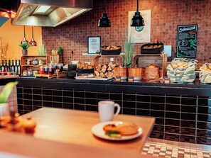 A café counter with a variety of baked goods, a menu board, and a coffee machine.
