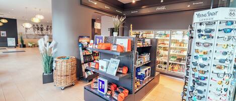 Un interior moderno con un mostrador de recepción, estanterías con productos y una exhibición de gafas de sol.