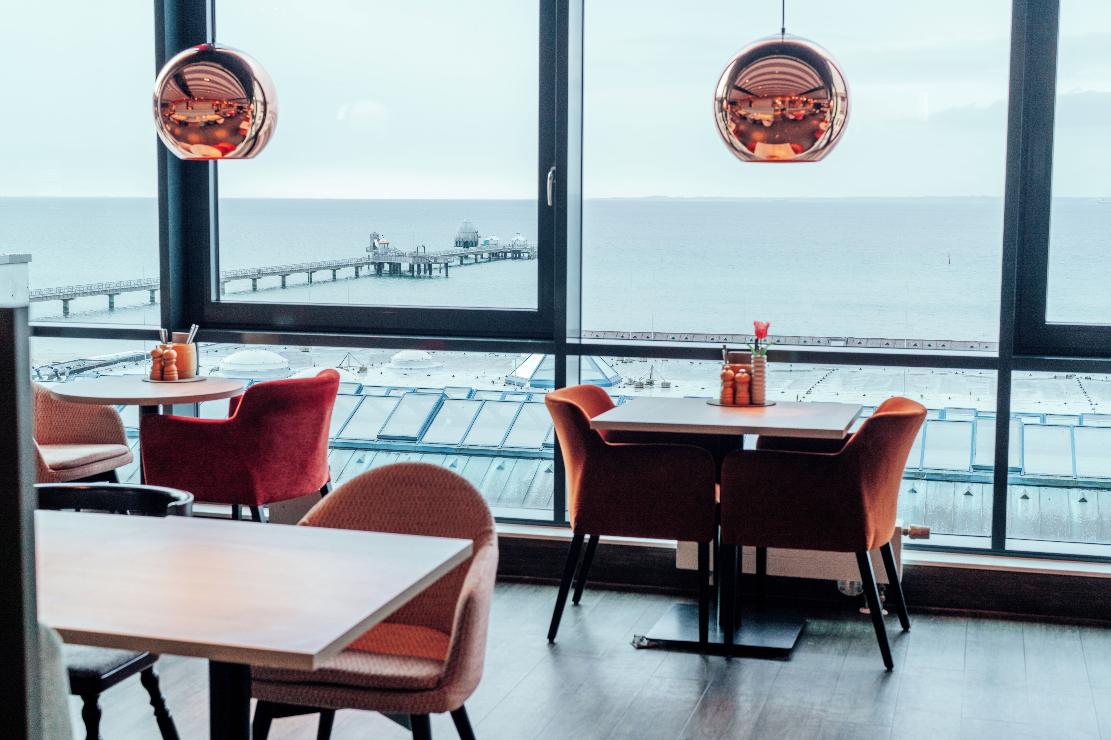Ein Restaurant mit großen Fenstern und Meerblick sowie einem Steg.