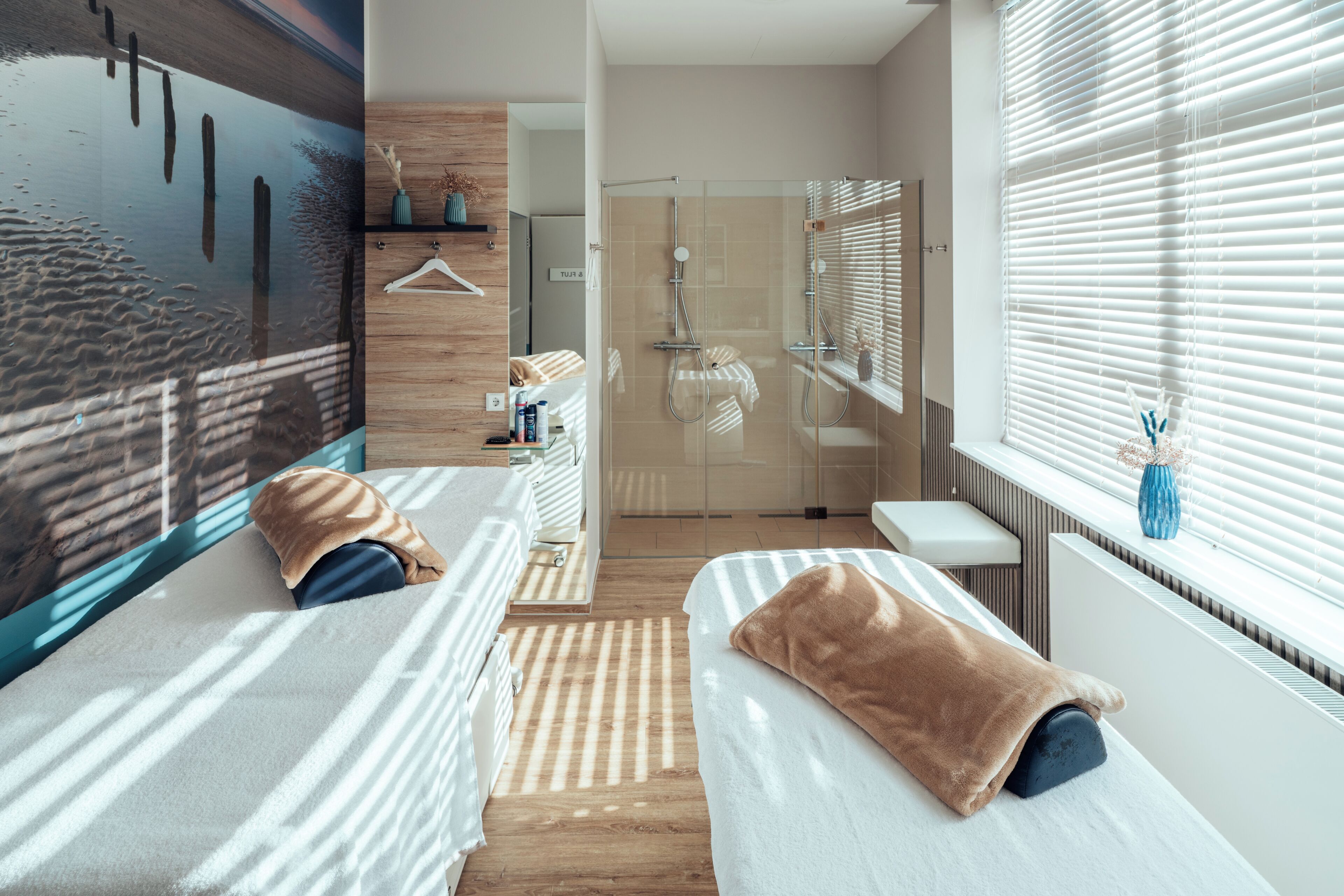 A modern hotel room with two beds, a shower, a view of the city, and a wooden floor.