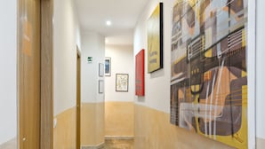 A hallway with wooden flooring, white walls, and artwork. - Vaticano84 (Rome)