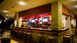 A bar area with stools, a counter, and a stone wall. - Real Palace (Hersonissos)