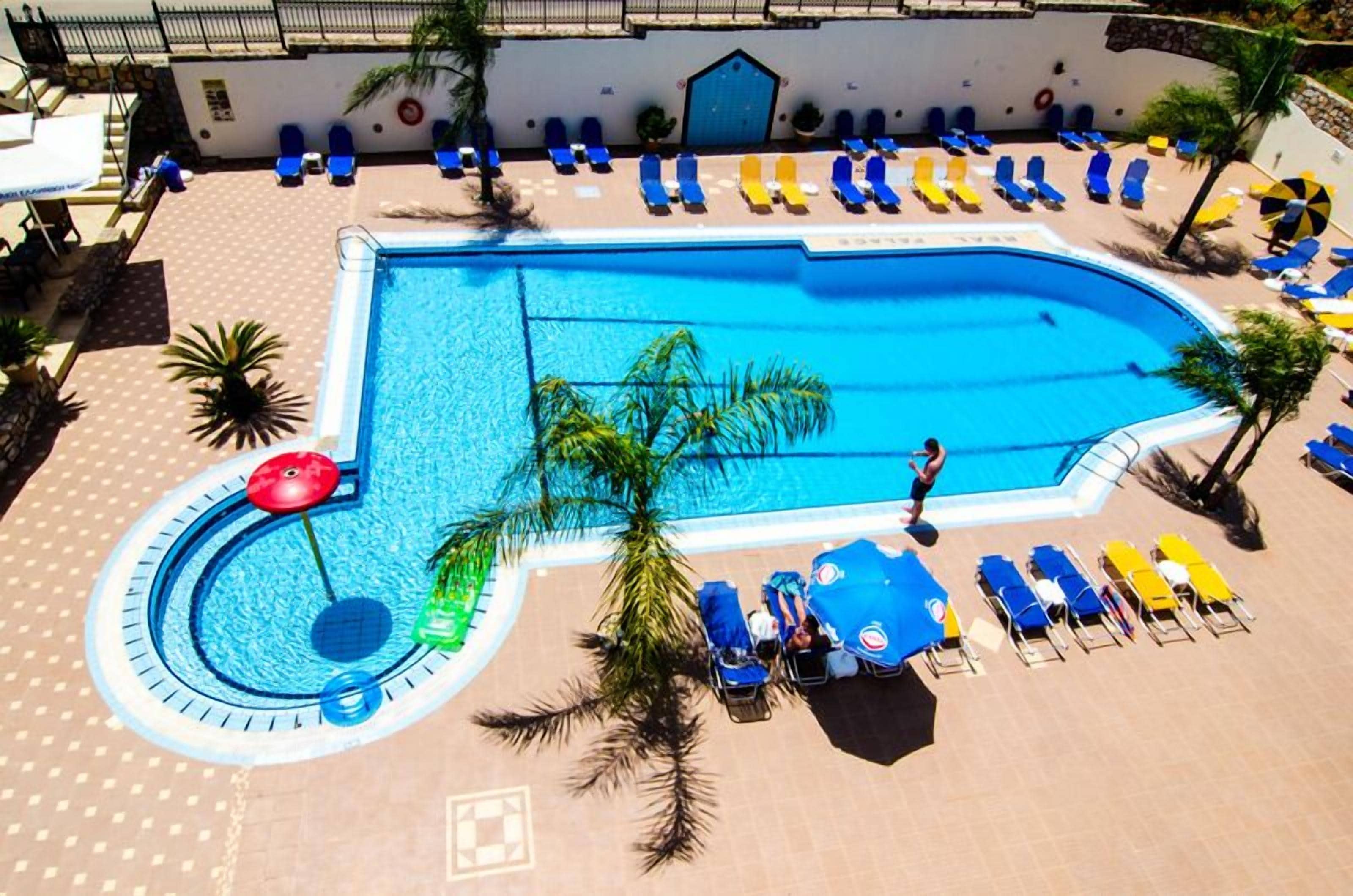 A swimming pool with blue water, surrounded by lounge chairs and umbrellas.