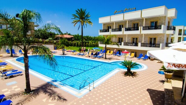Un hotel con piscina, tumbonas y palmeras.