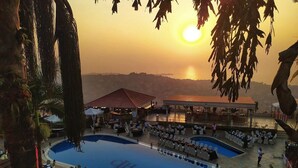 A resort with a large pool, outdoor seating, and a view of the sunset. - The Country Lodge Hotel (Freetown)