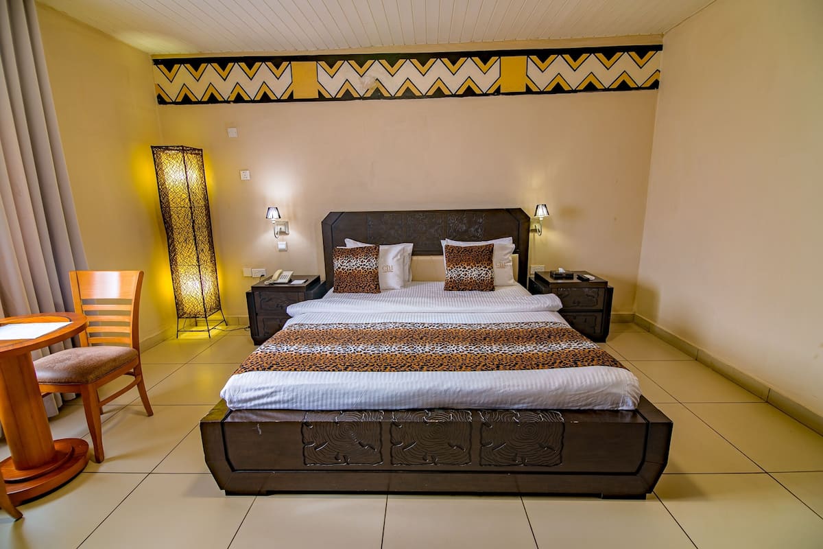 Ein Hotelzimmer mit einem großen Bett, Nachttischen, einem Schreibtisch und einem Sessel.