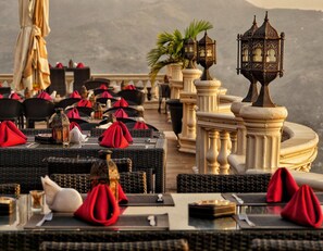 A restaurant with outdoor seating, wicker tables, red napkins, and ornate lanterns. - The Country Lodge Hotel (Freetown)