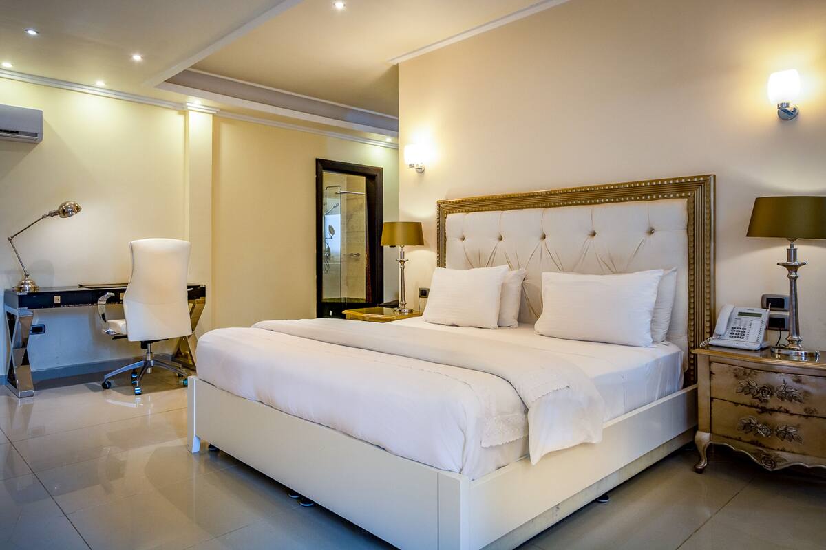 Ein geräumiges Hotelzimmer mit einem großen Bett, Nachttischen, einem Schreibtisch und einem Sessel.