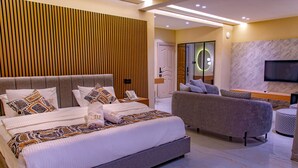 A modern bedroom with a large bed, a sofa, and a TV. - The Country Lodge Hotel (Freetown)