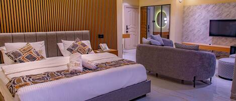 A modern bedroom with a large bed, a sofa, and a TV.