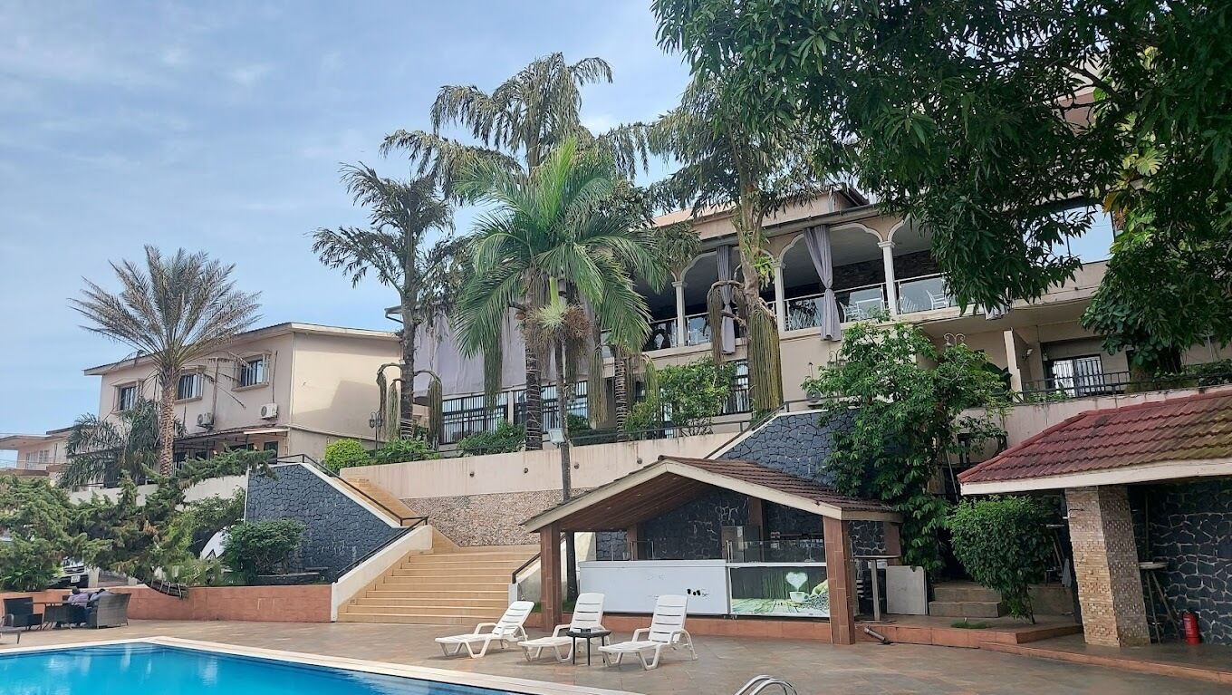 A resort with a swimming pool, lounge chairs, and a covered area with a view of the pool.