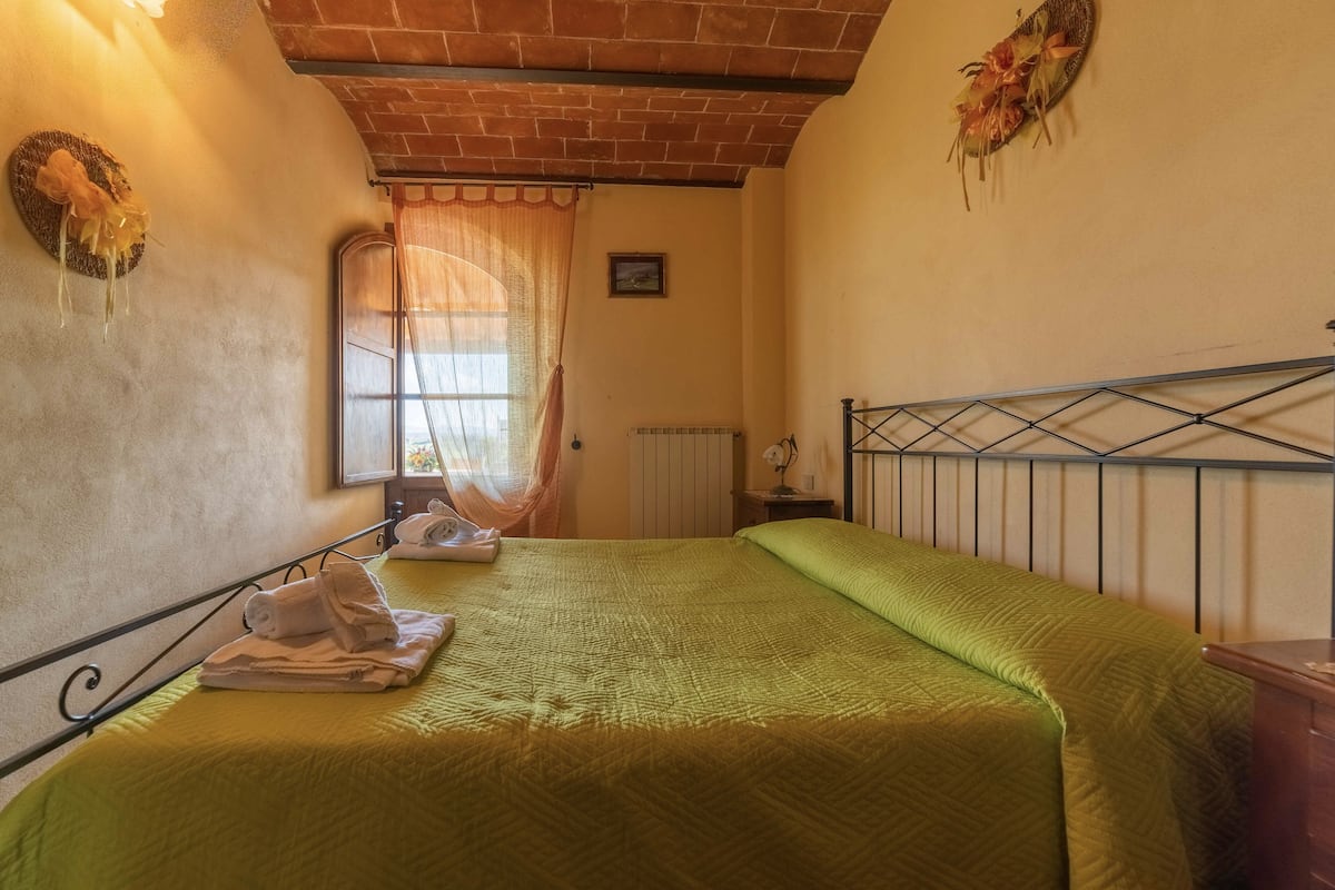 Ein Zimmer mit zwei Betten, einer Ziegeldecke, einem Fenster mit Vorhängen, einem Heizkörper und einer Wanddekoration.