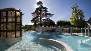 A swimming pool with clear water, surrounded by a glass structure and trees. - Agriturismo Podere Diacceroni (Peccioli)
