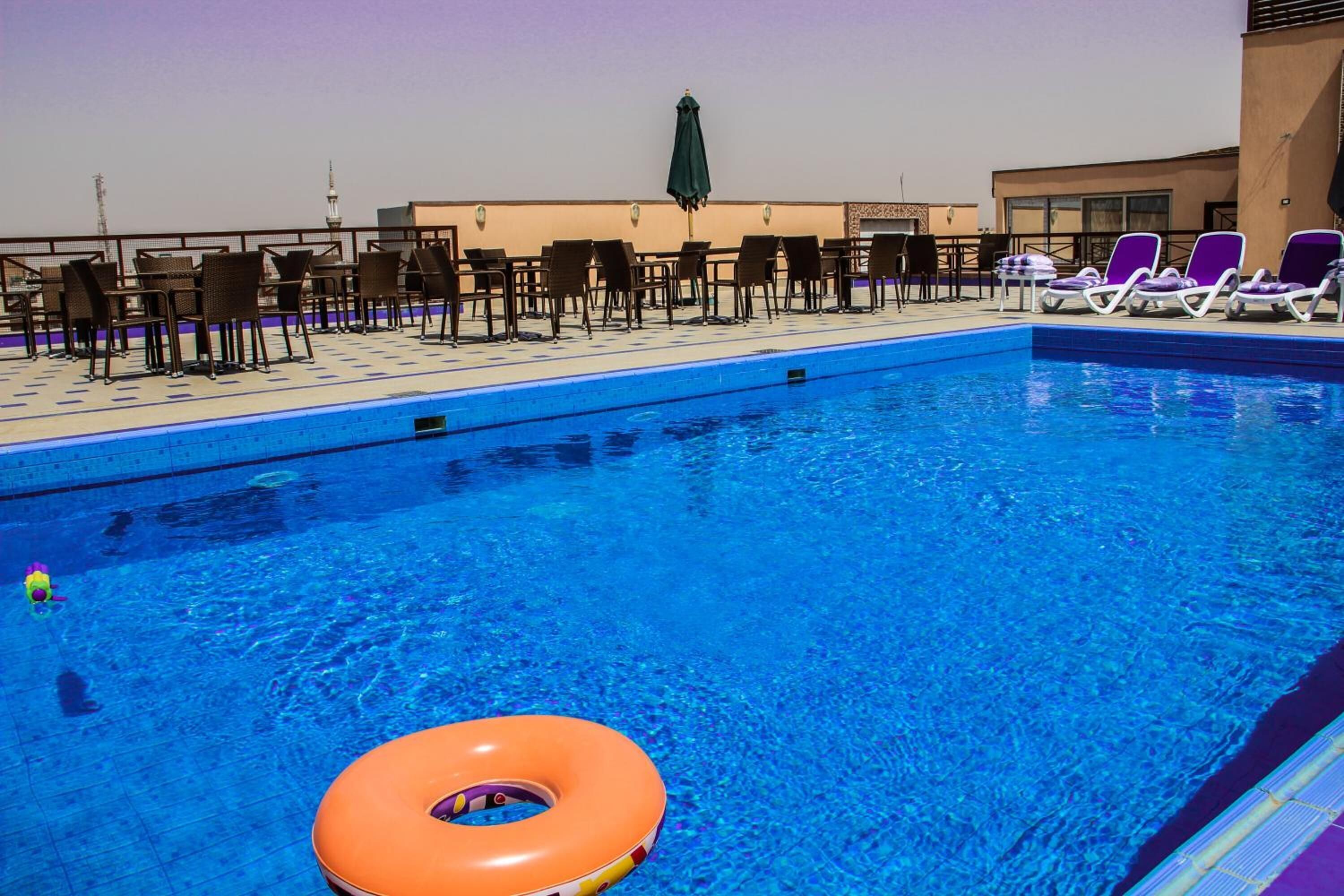 A swimming pool with lounge chairs and a sun umbrella.
