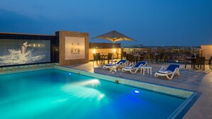 A rooftop pool area with lounge chairs, a dining table, and a large mural. - Mirita Hotel (Tenth of Ramadan City)
