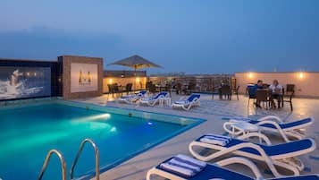 Alberca al aire libre, sombrillas en la alberca y camastros