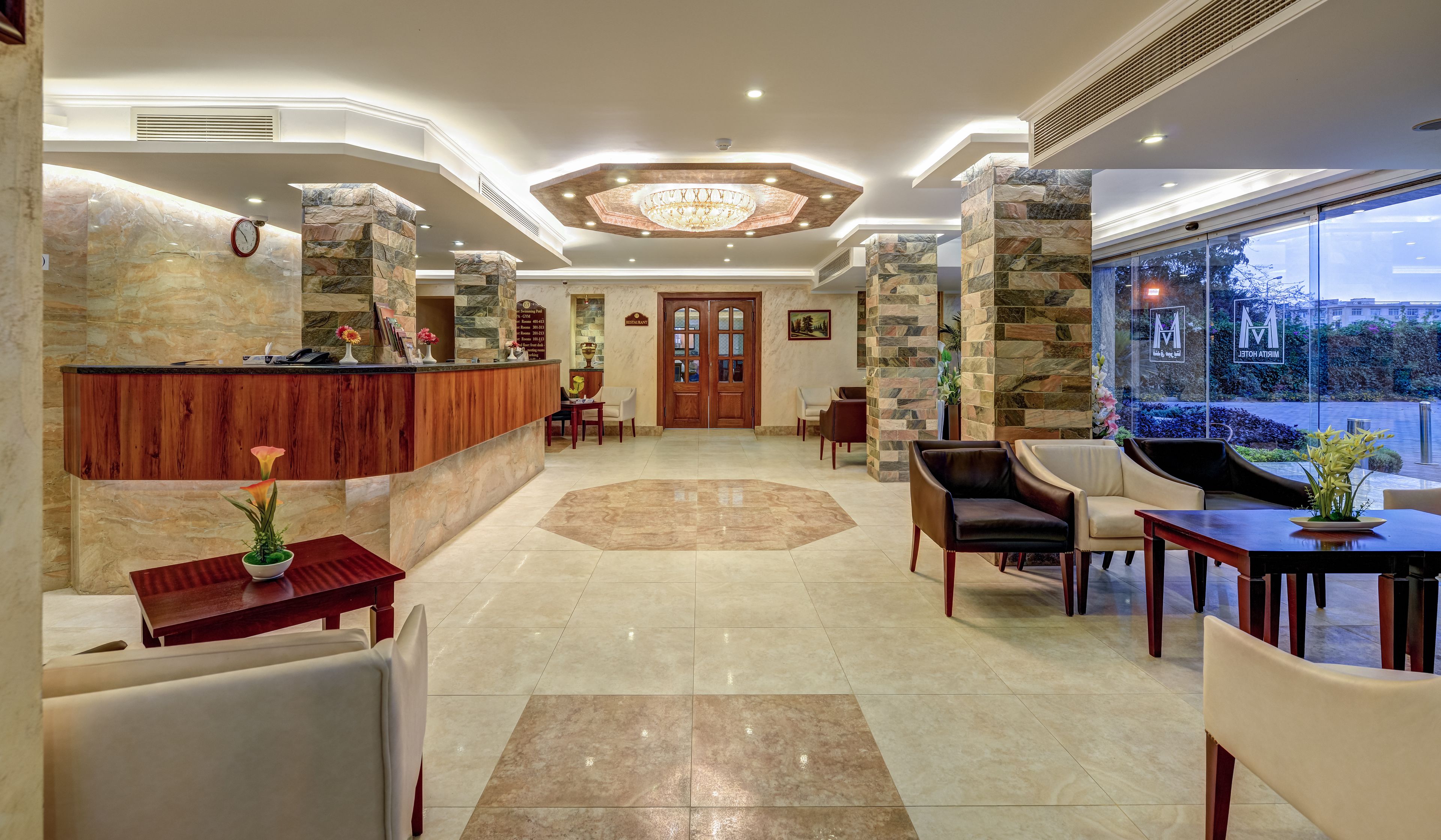 A hotel lobby with a reception desk, seating area, and a view of the outdoors.