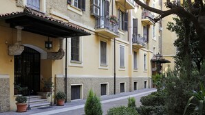 A courtyard with a yellow building, potted plants, and a tree.