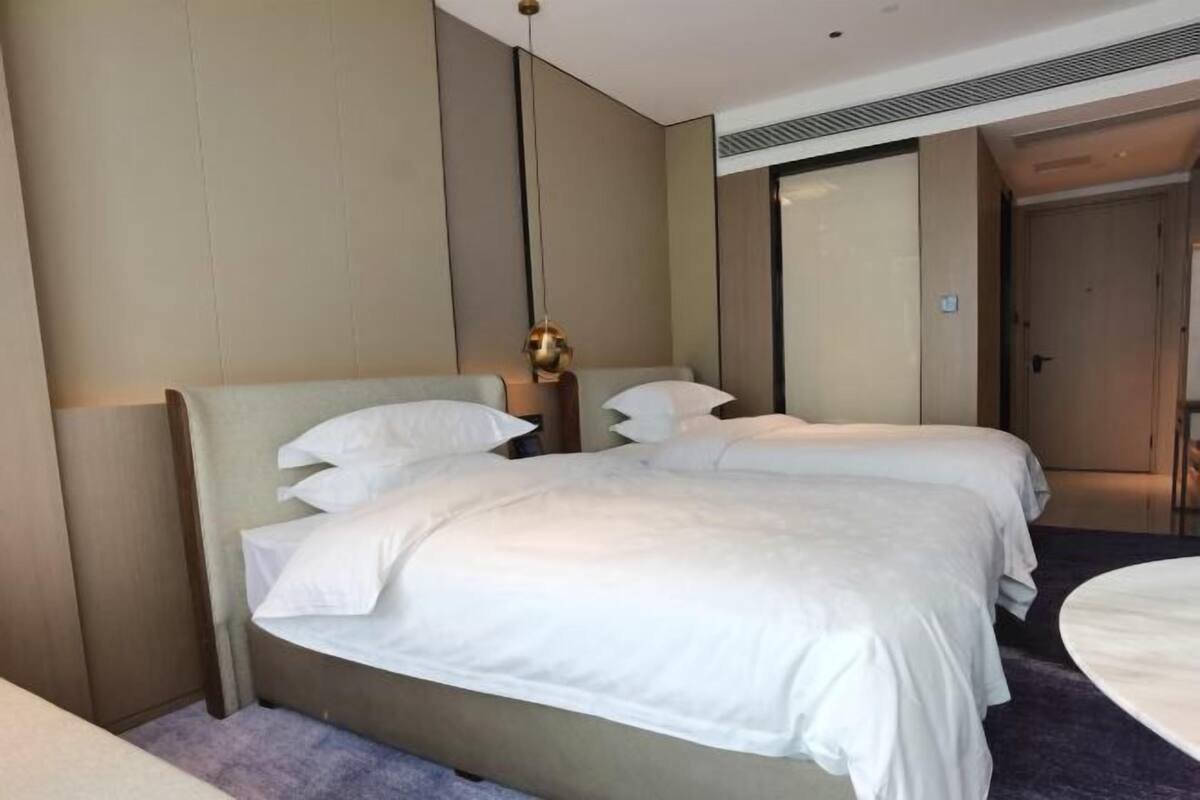 Ein Hotelzimmer mit einem großen Bett, einem Nachttisch, einem Spiegel und einer Tür.