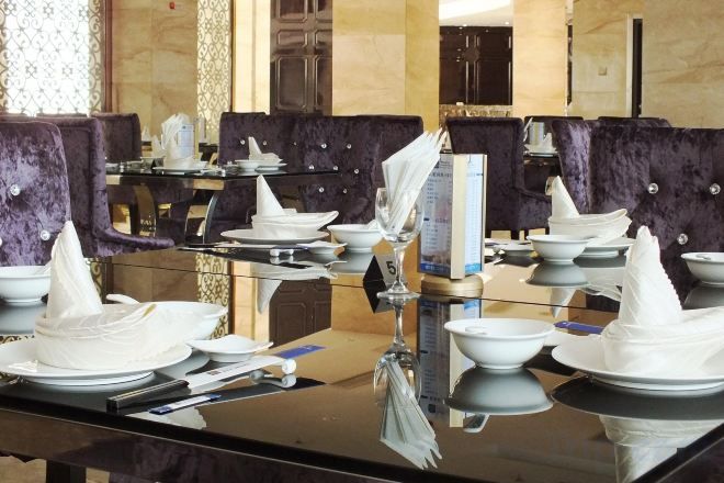 Un comedor con varias mesas dispuestas para el servicio, cada una con platos blancos, cubiertos y servilletas dobladas.