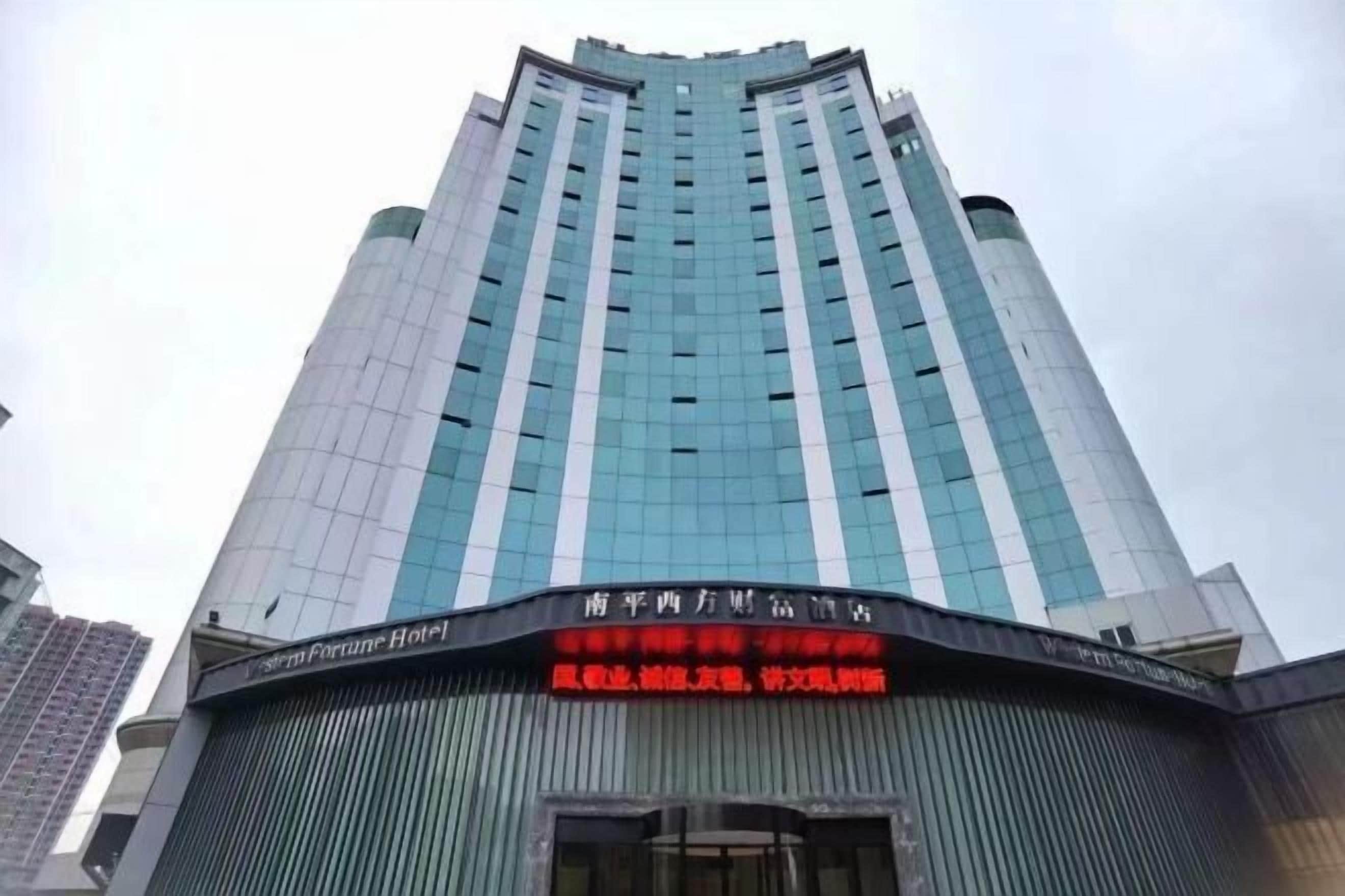 Un edificio de hotel alto con fachada de vidrio moderna y un cartel que indica que es el Fortune Hotel.