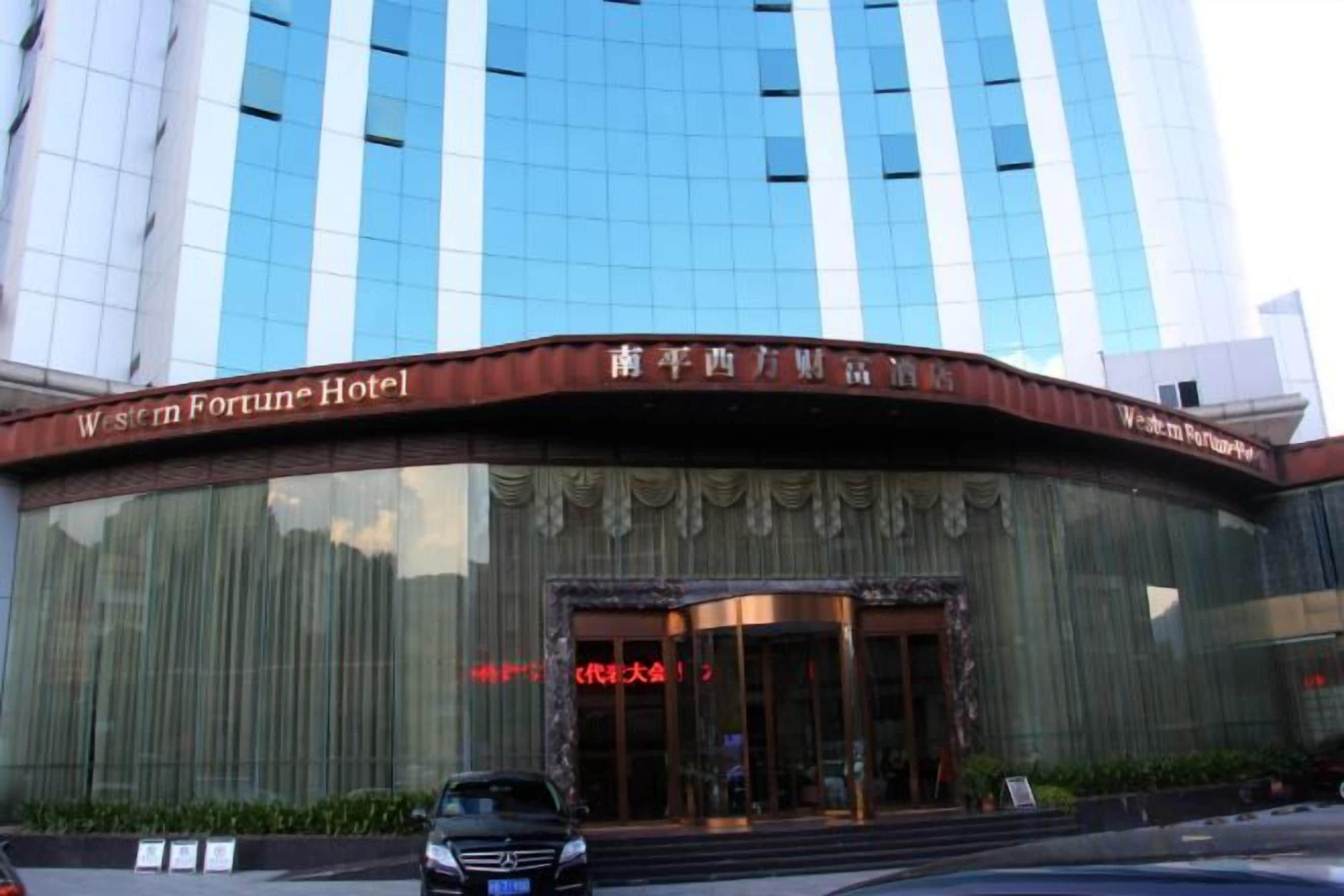 Et hotel med en buet facade, store glasruder og et skilt, der angiver, at det er Western Fortune Hotel.