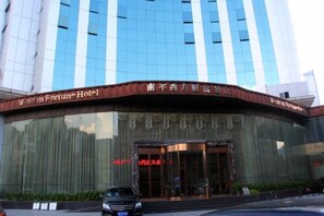 Un hotel con fachada curva, amplias ventanas de vidrio y un letrero que indica que es el Western Fortune Hotel.