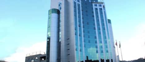 A multi-story hotel with a modern design, featuring a prominent vertical element on the left side and a reflective glass facade.