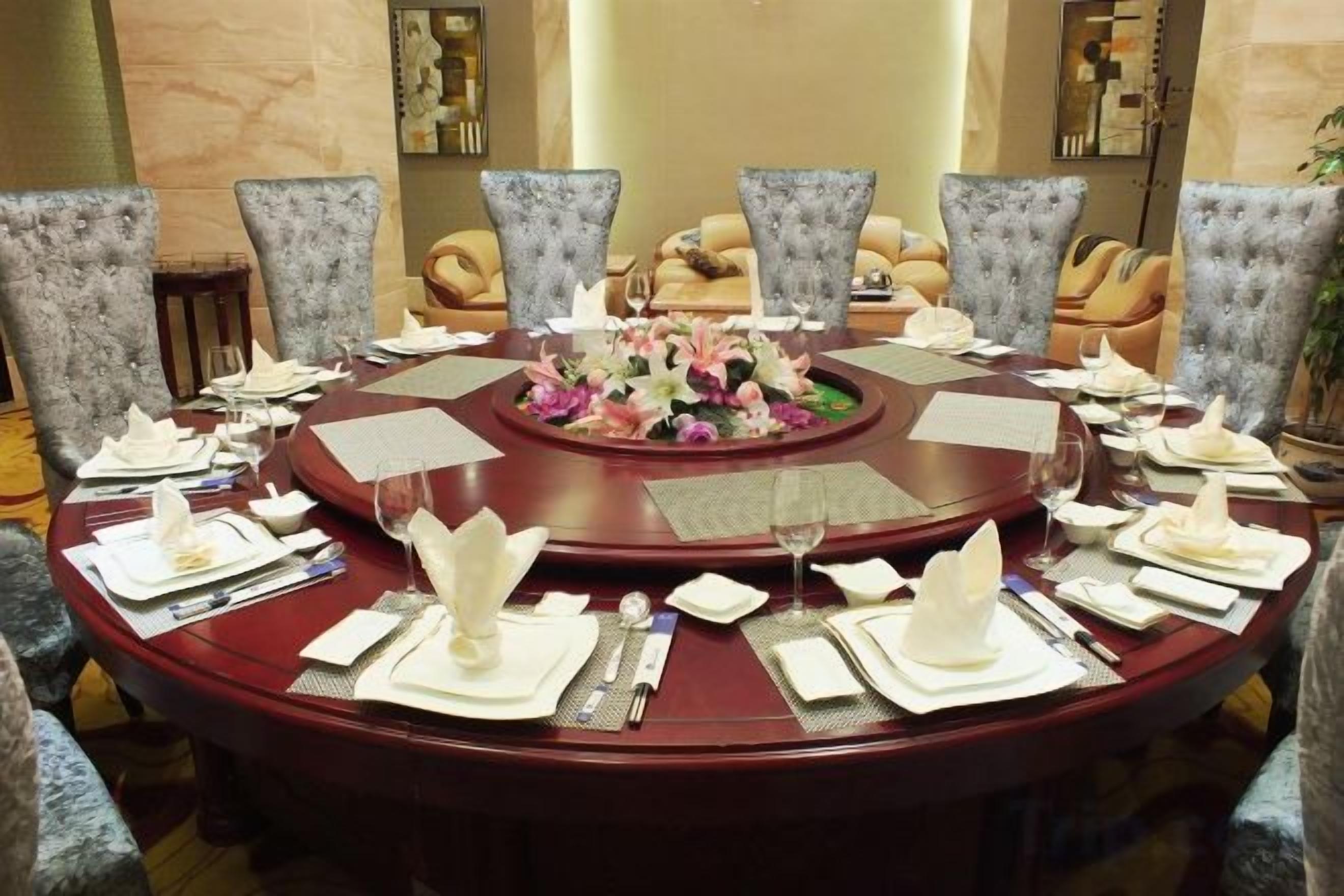 Una mesa de comedor redonda con un centro de mesa floral, rodeada de sillas tapizadas.