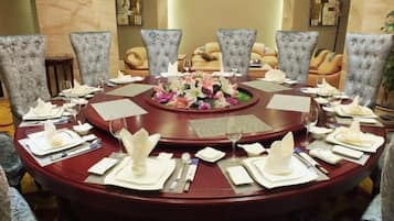 Una mesa de comedor redonda con un centro de mesa floral, rodeada de sillas tapizadas.
