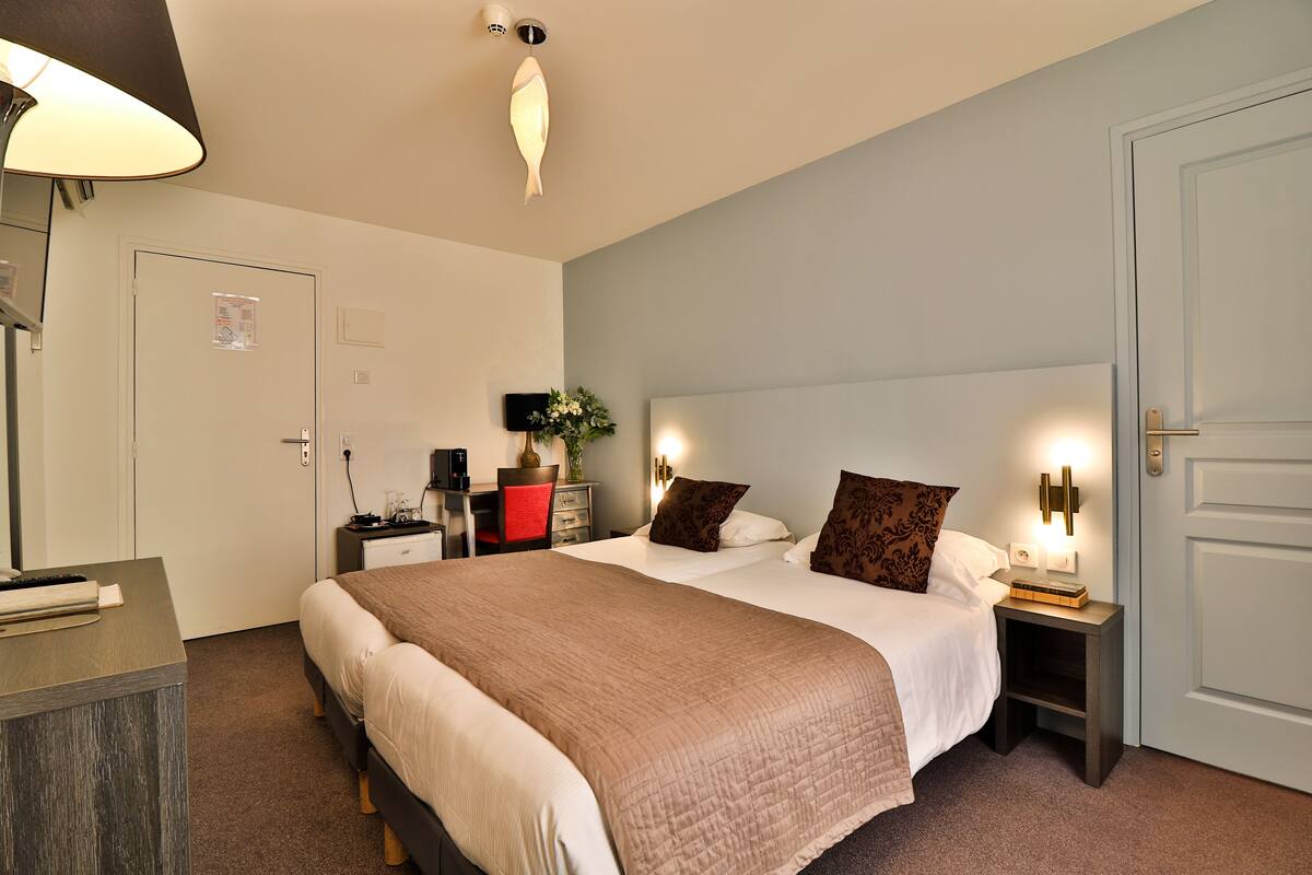 A hotel room with a large bed, bedside tables, a desk, and a chair.