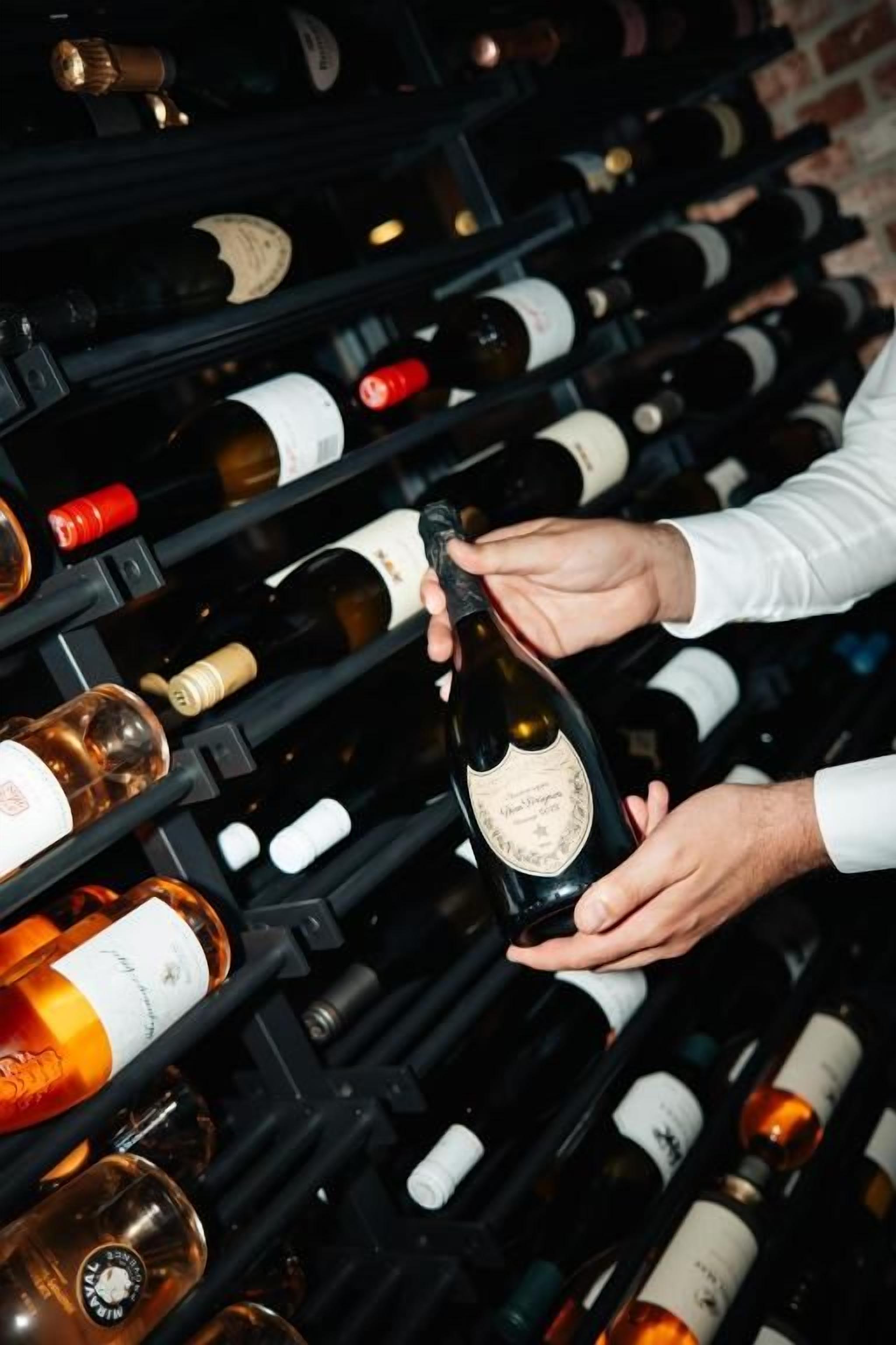 Une personne tenant une bouteille de vin dans un porte-bouteilles.