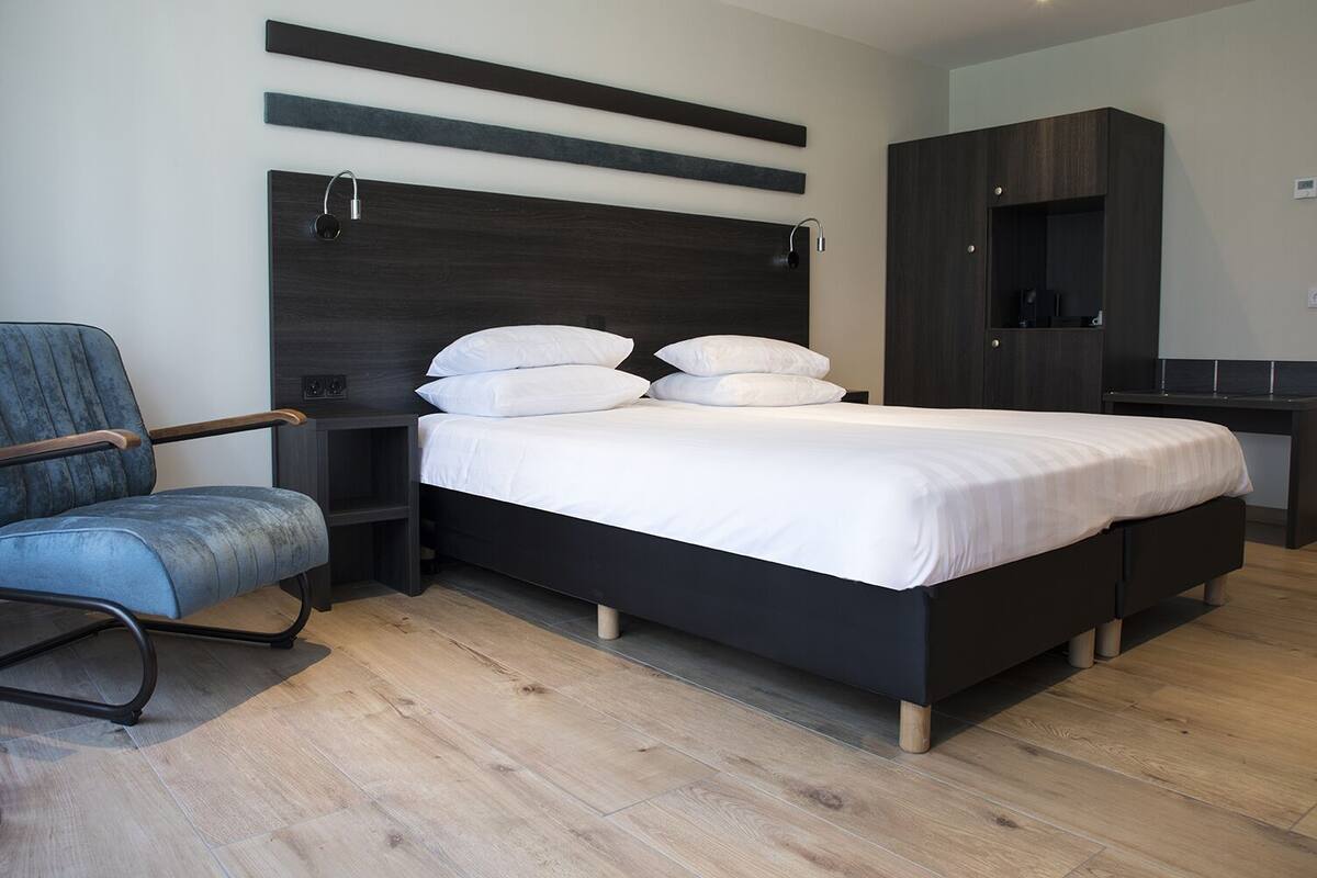 Ein modernes Schlafzimmer mit Bett, Stuhl, Nachttisch und Kleiderschrank.